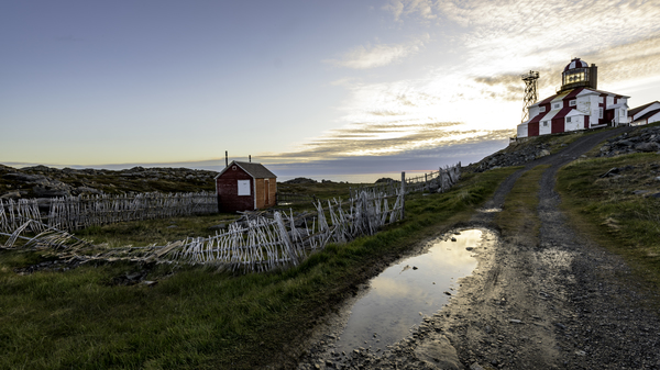 Road leading up to a red and white striped lighthouse on Cape Bonavista in Newfoundland and Labrador, Canada.