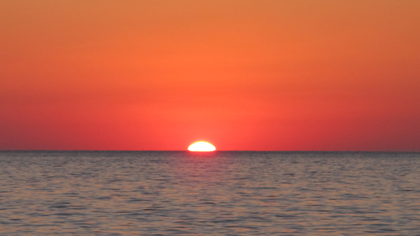 Top of Sun showing above the horizon.